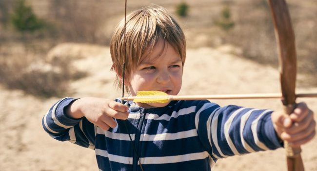 Boy 6 year old shoots a bow in the open air.