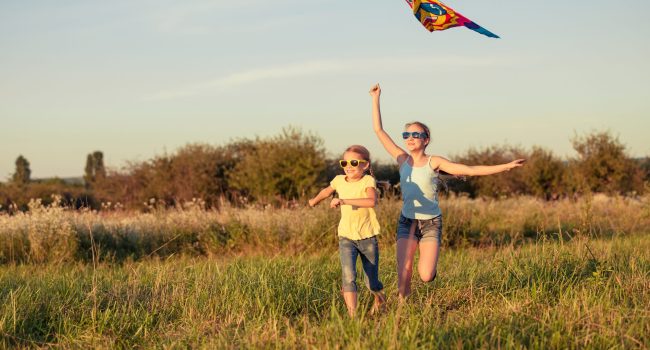 Happy children playing on the field at the day time. Concept of friendly siblings of family.